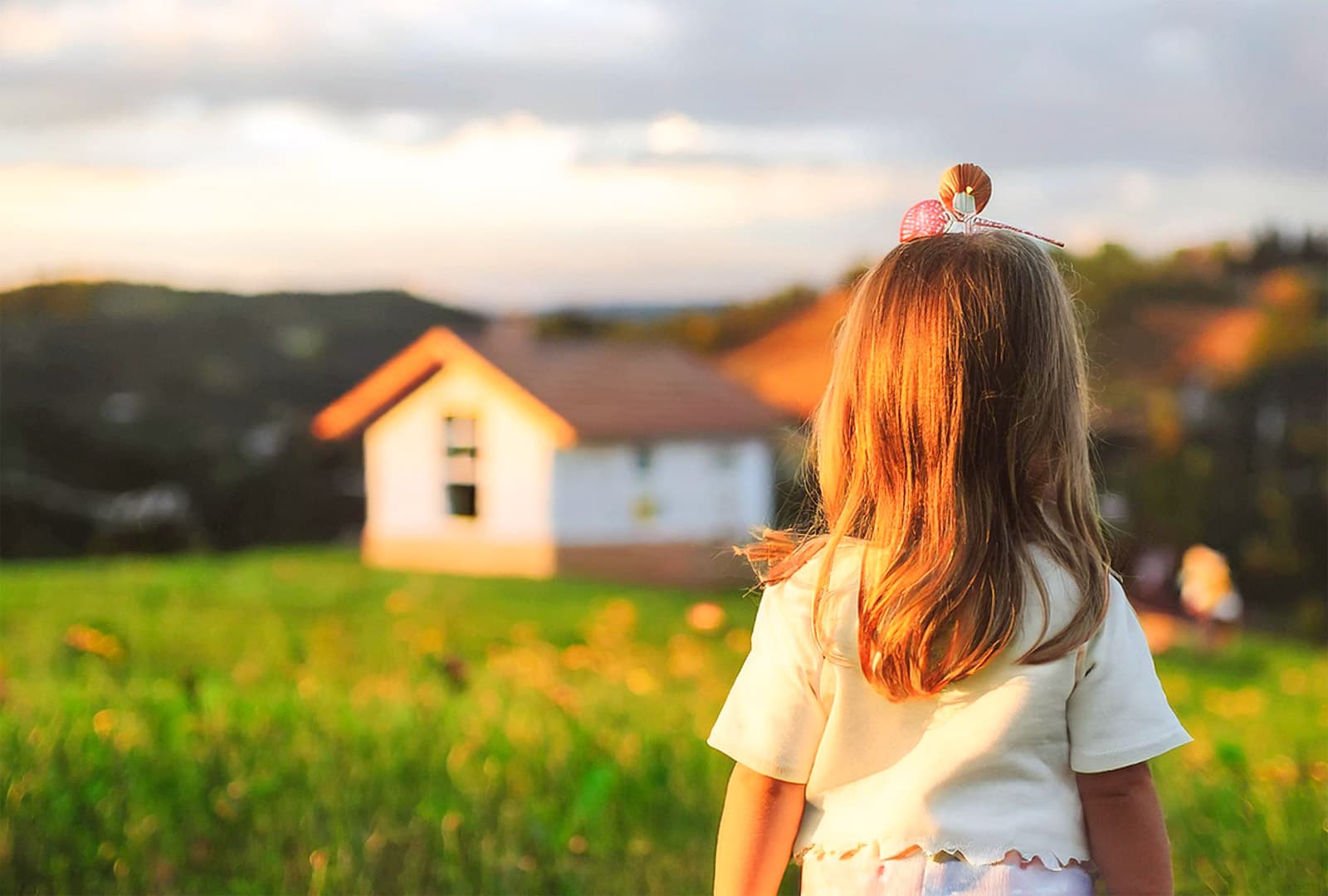 Bambina guarda l'orizzonte in un prato